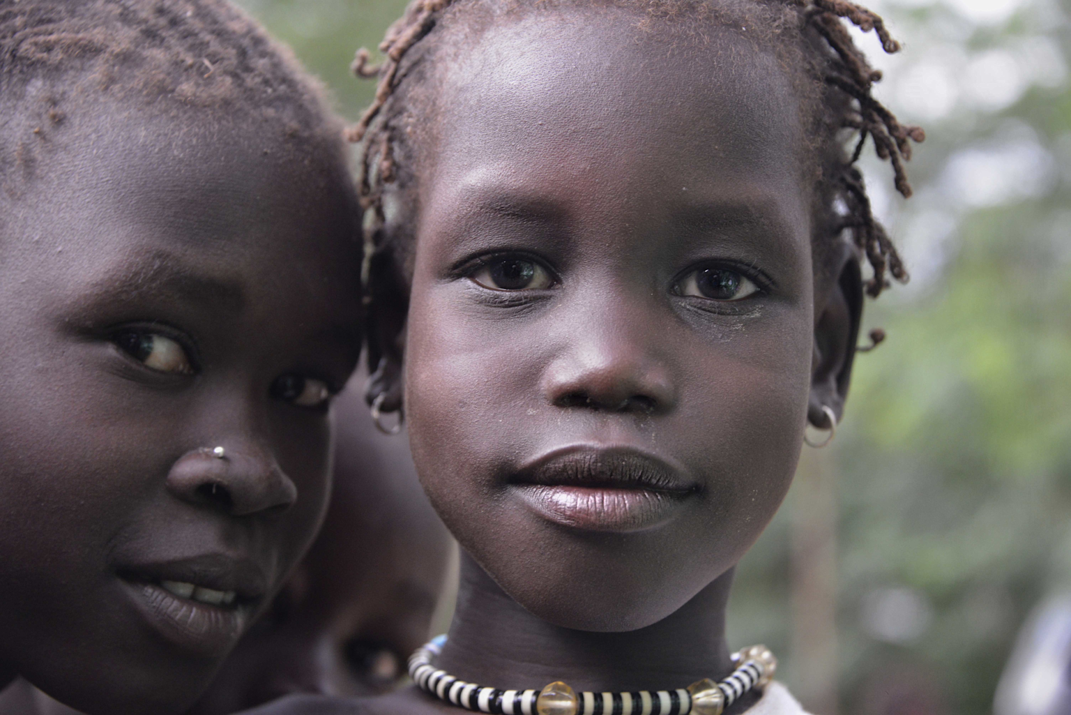 Close-up of an Anuak individual with traditional hairstyle and beads symbolizing cultural identity in Ethiopia's Gambella region